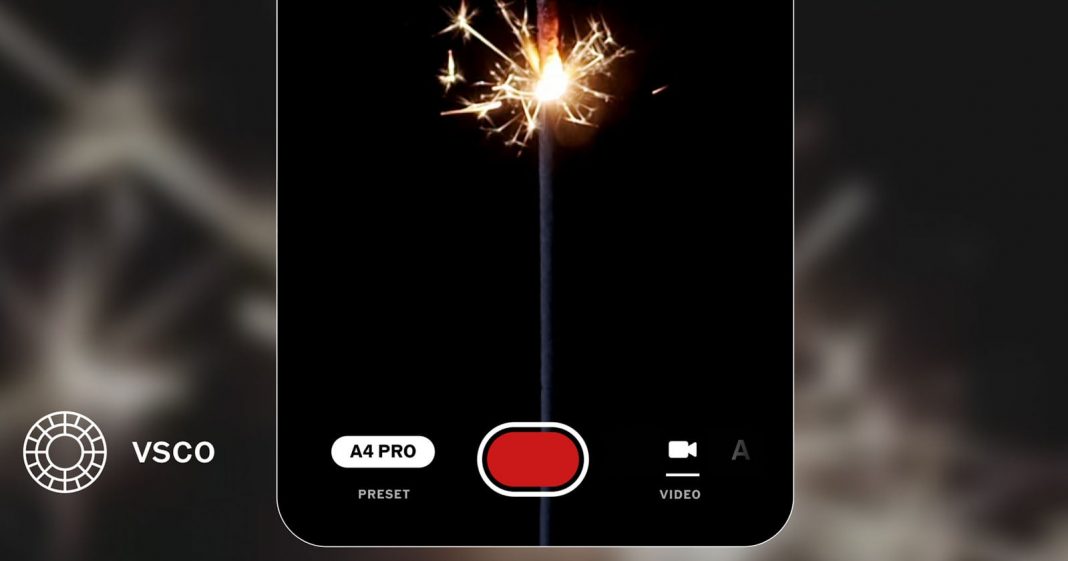 VSCO Wraps Up 2025 By Adding Video Recording to its A smartphone screen displays a photo of a lit sparkler against a black background. Camera app controls are visible, including a red shutter button, "A4 PRO" preset, and the VSCO logo in the corner.