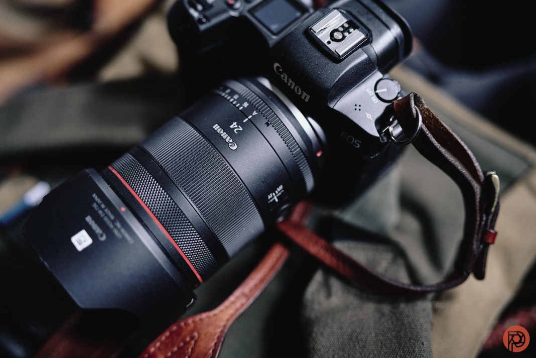 My Canon EOS R Needed a Repair. Here's How I Close-up of a Canon EOS camera with a 24mm lens resting on a green and brown fabric surface.