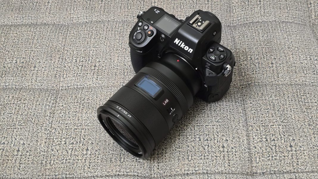 A Nikon Z series digital camera with a NIKKOR lens resting on a textured gray surface.