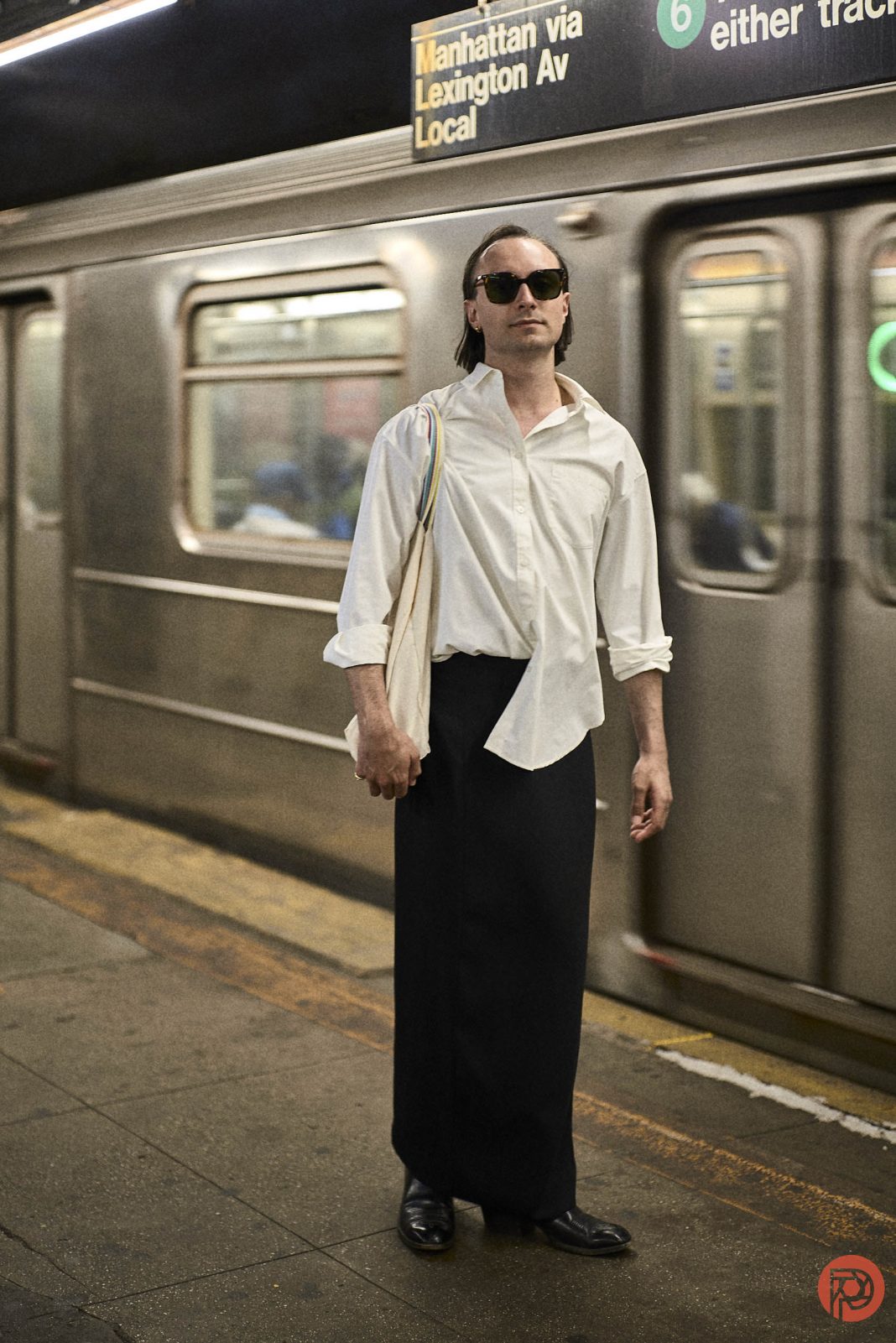 Make Your Photos Look Like Retro, For Free With Our A person in a white shirt and long black skirt stands on a subway platform with a train in the background.