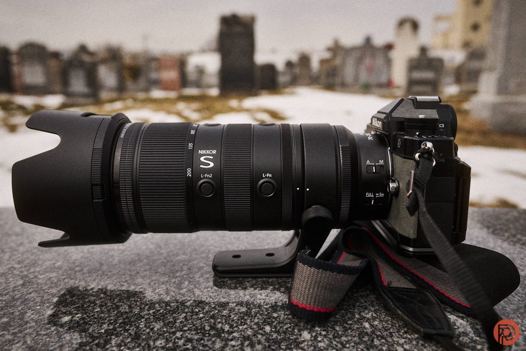 Nikon Z 70-200mm f2.8 S VR II Review: Nikon's Best A black DSLR camera with a large telephoto lens sits on a stone surface in a cemetery.