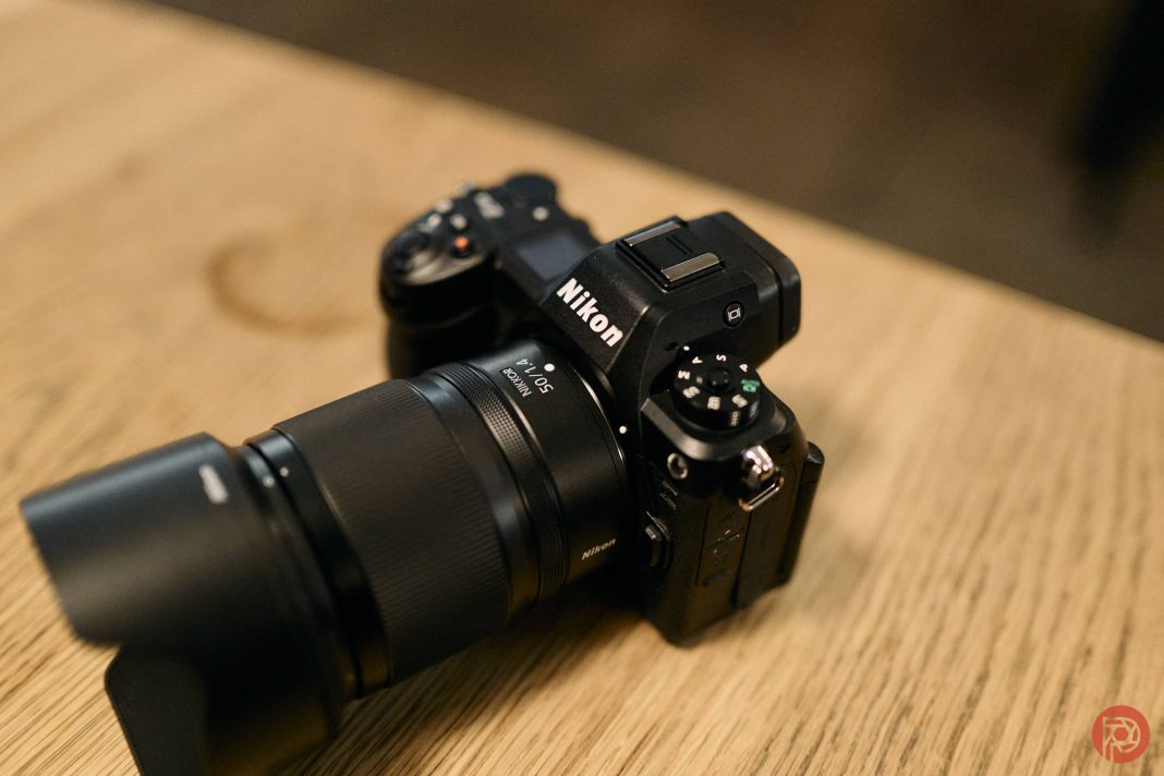 A Nikon mirrorless camera with a lens, resting on a wooden surface.
