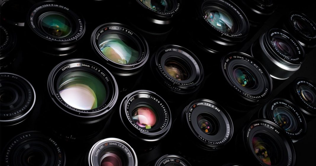 A close-up view of multiple camera lenses arranged closely together, showing their glass elements and reflections, with various brand markings visible on the lens rims.